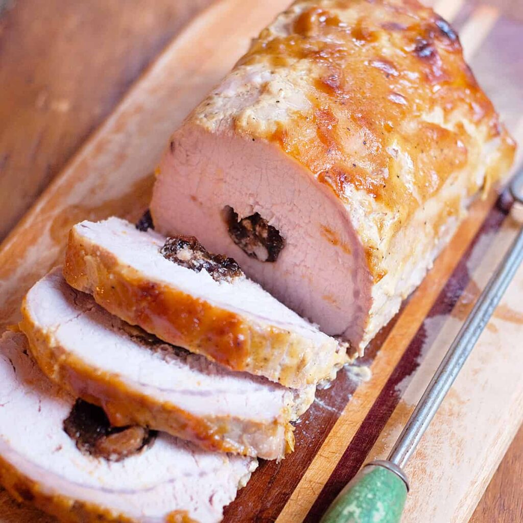 Cooked stuffed pork loin on a cutting board.