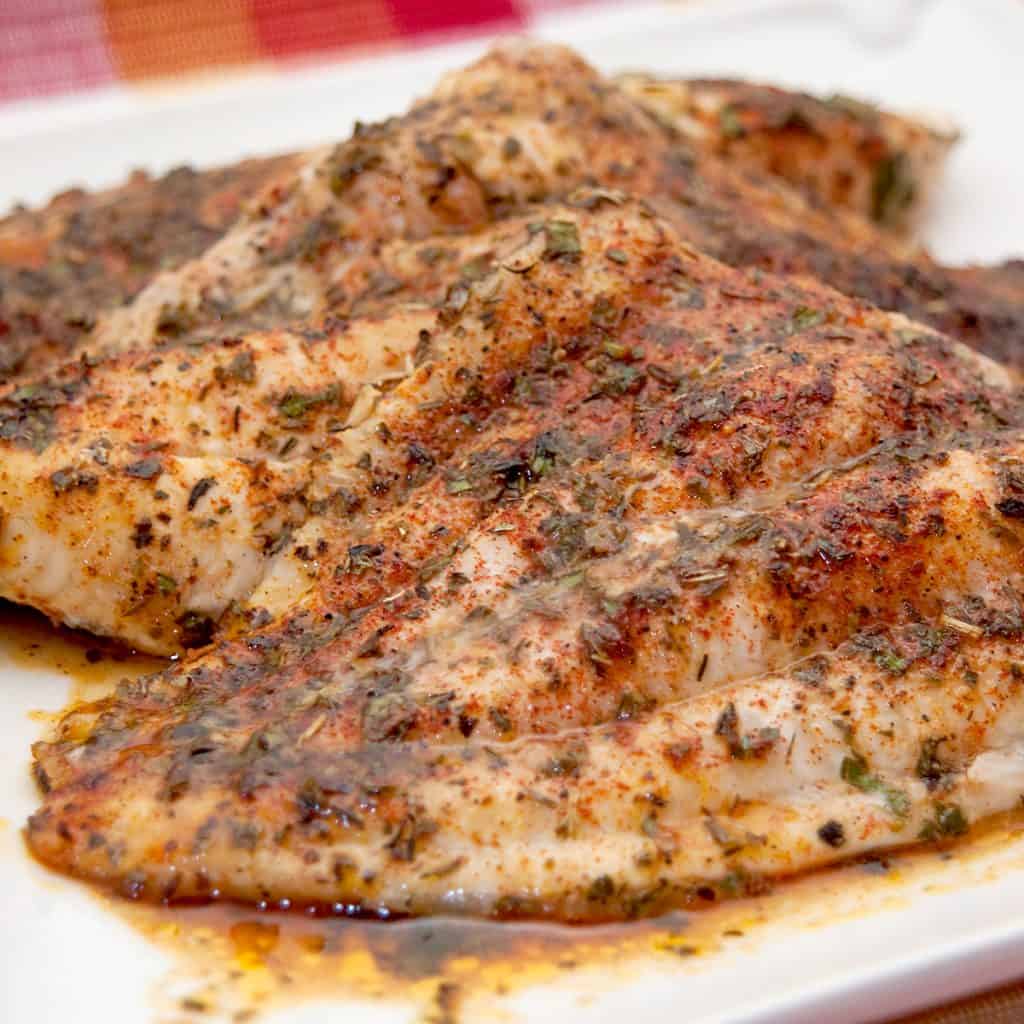 Baked catfish on a white serving plate.