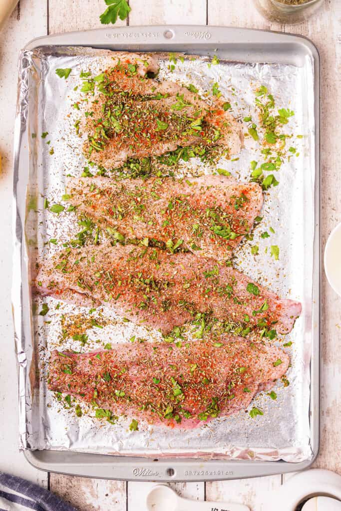 Fish fillets on a pan sprinkled with herb mixture.