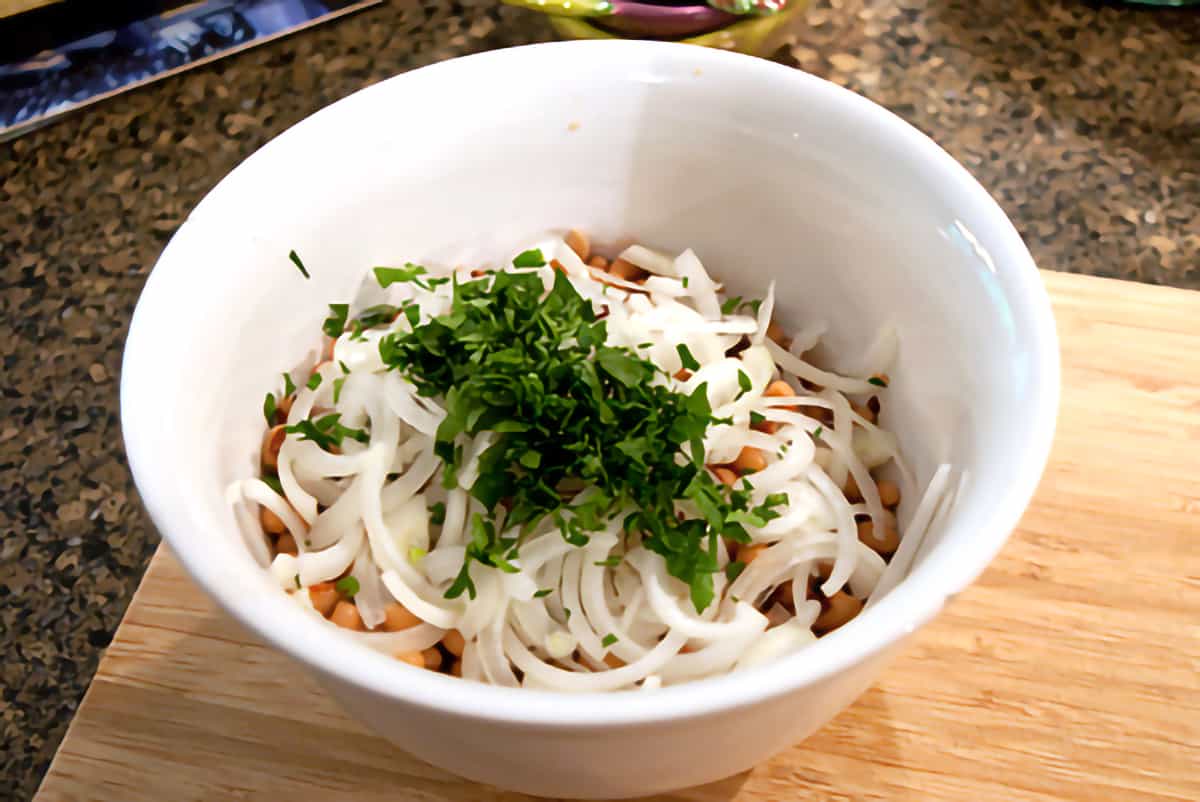 Peas, onion, and parsley in a white mixing bowl.