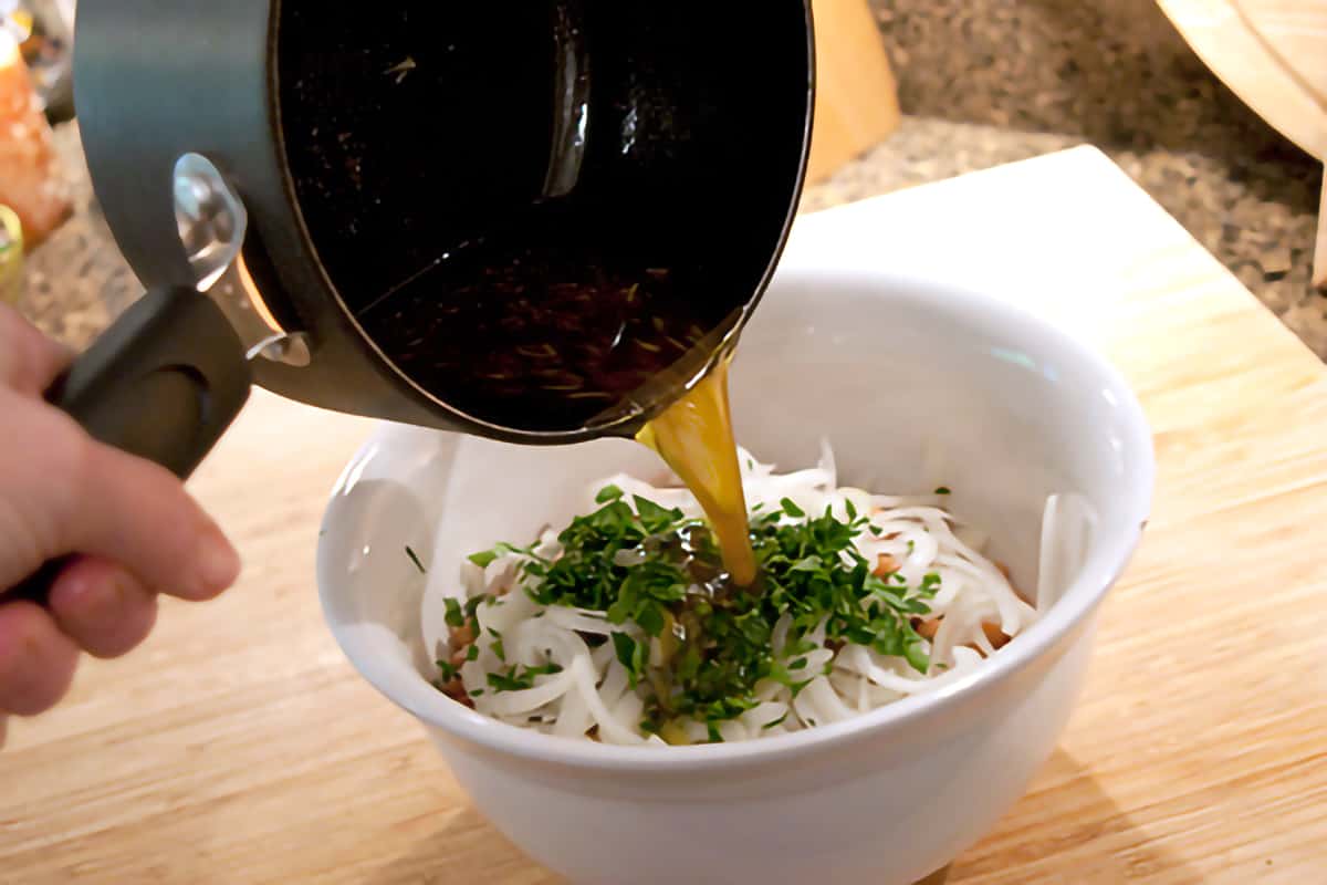 Hot marinade being poured over the ingredients in the mixing bowl.