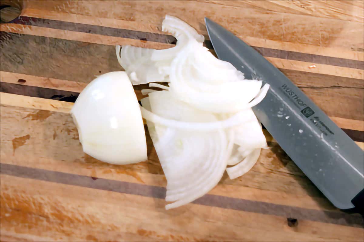 Thinly sliced onion on a small cutting board.