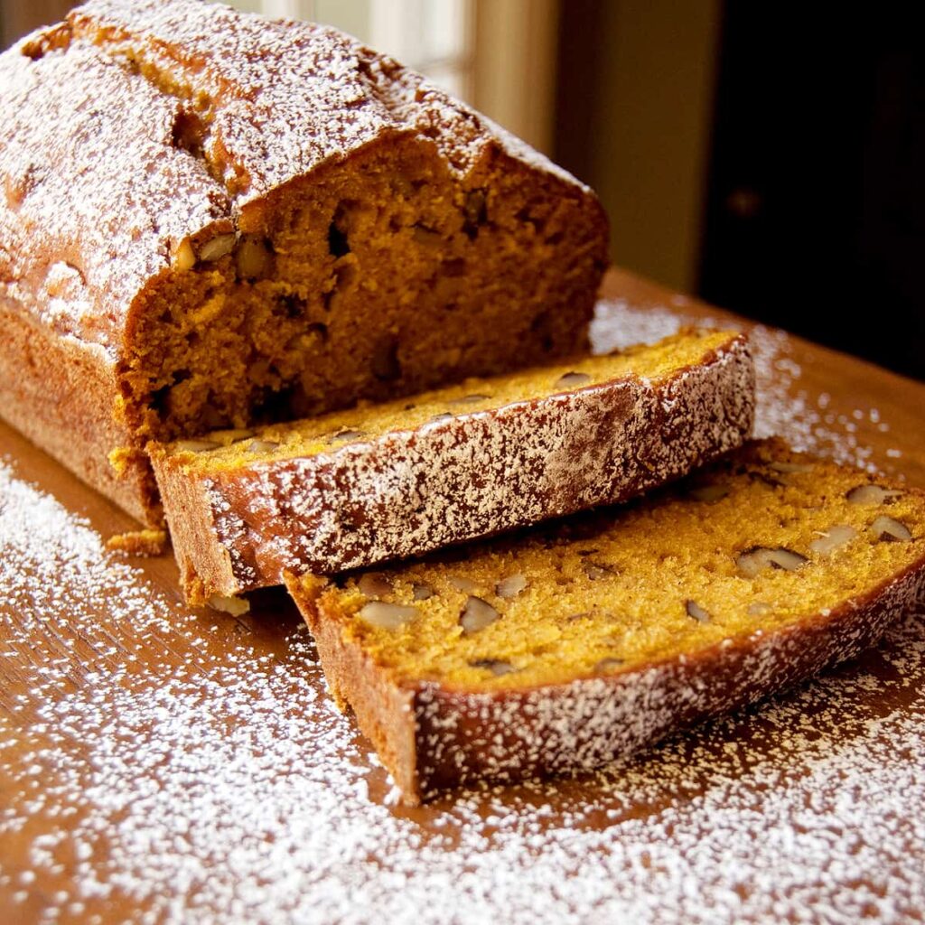 Sliced black walnut pumpkin bread on a serving board.