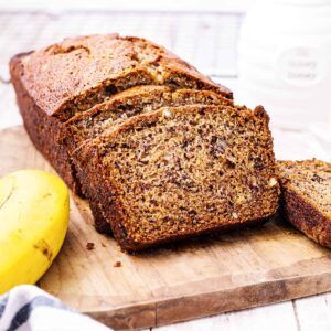 A loaf of Buttermilk Banana Nut Bread sliced and presented on a cutting board.