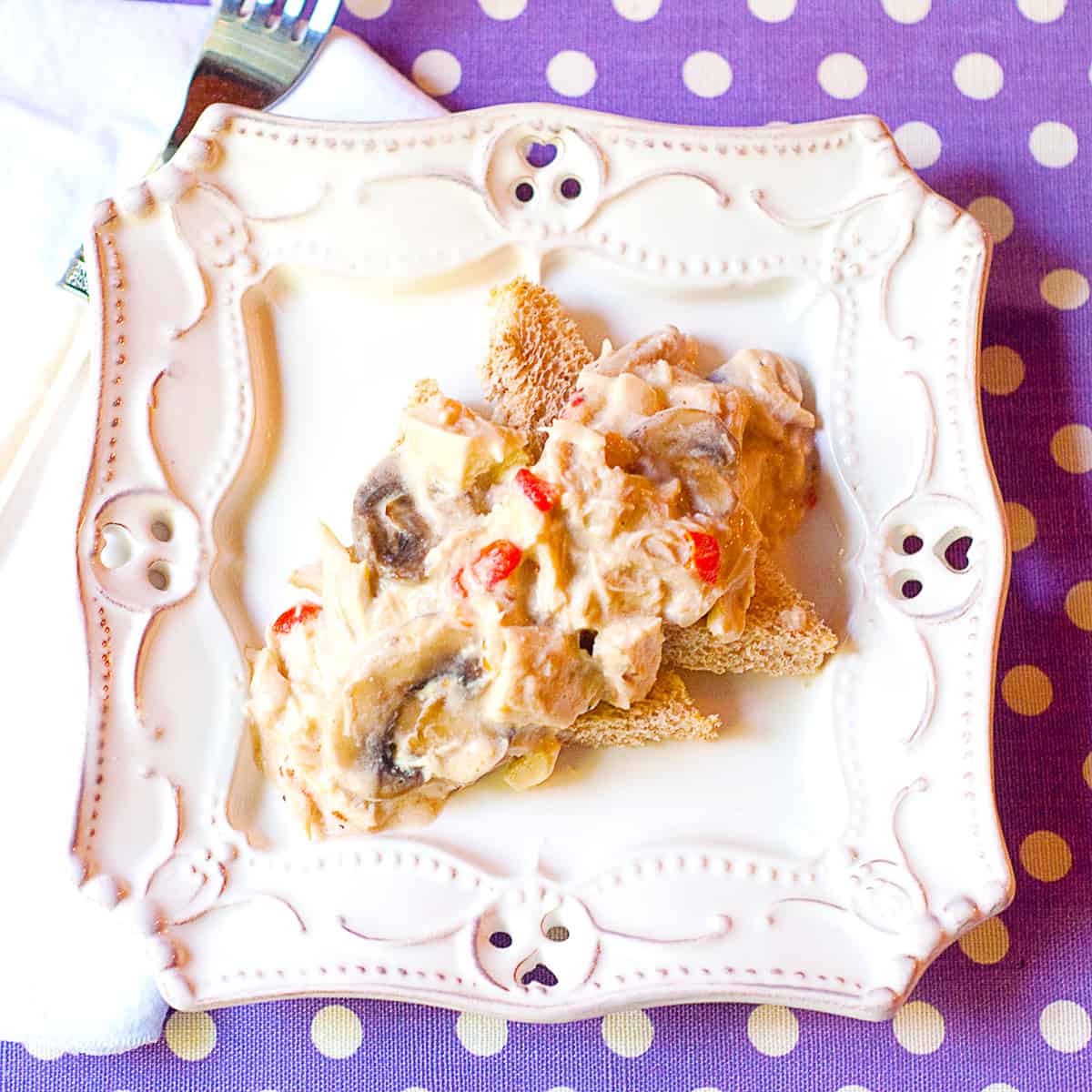 A serving of chicken a la king over toast points on a white plate.