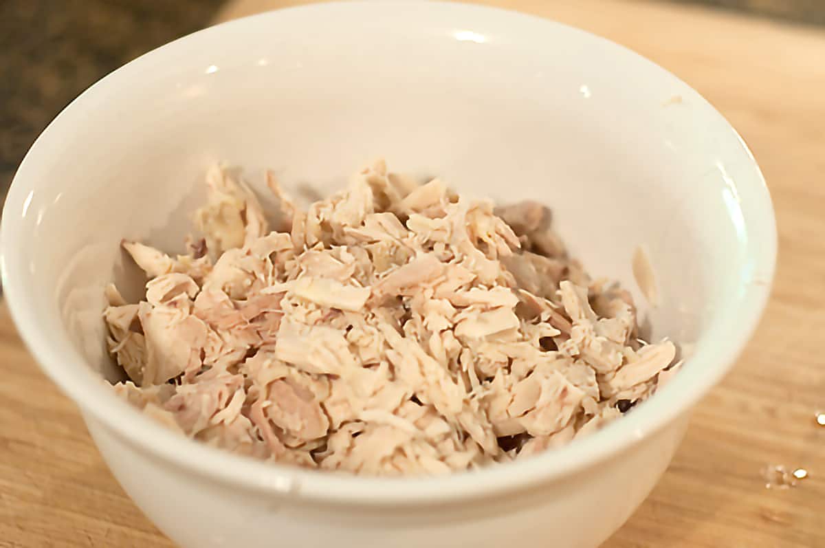 Shredded, deboned chicken in a white bowl.