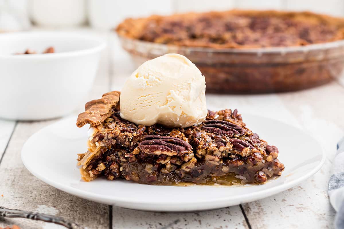 A slice of pecan pie with a scoop of vanilla ice cream.