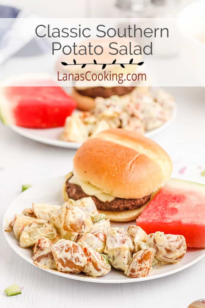 Southern potato salad on a white plate with a hamburger and slice of watermelon.