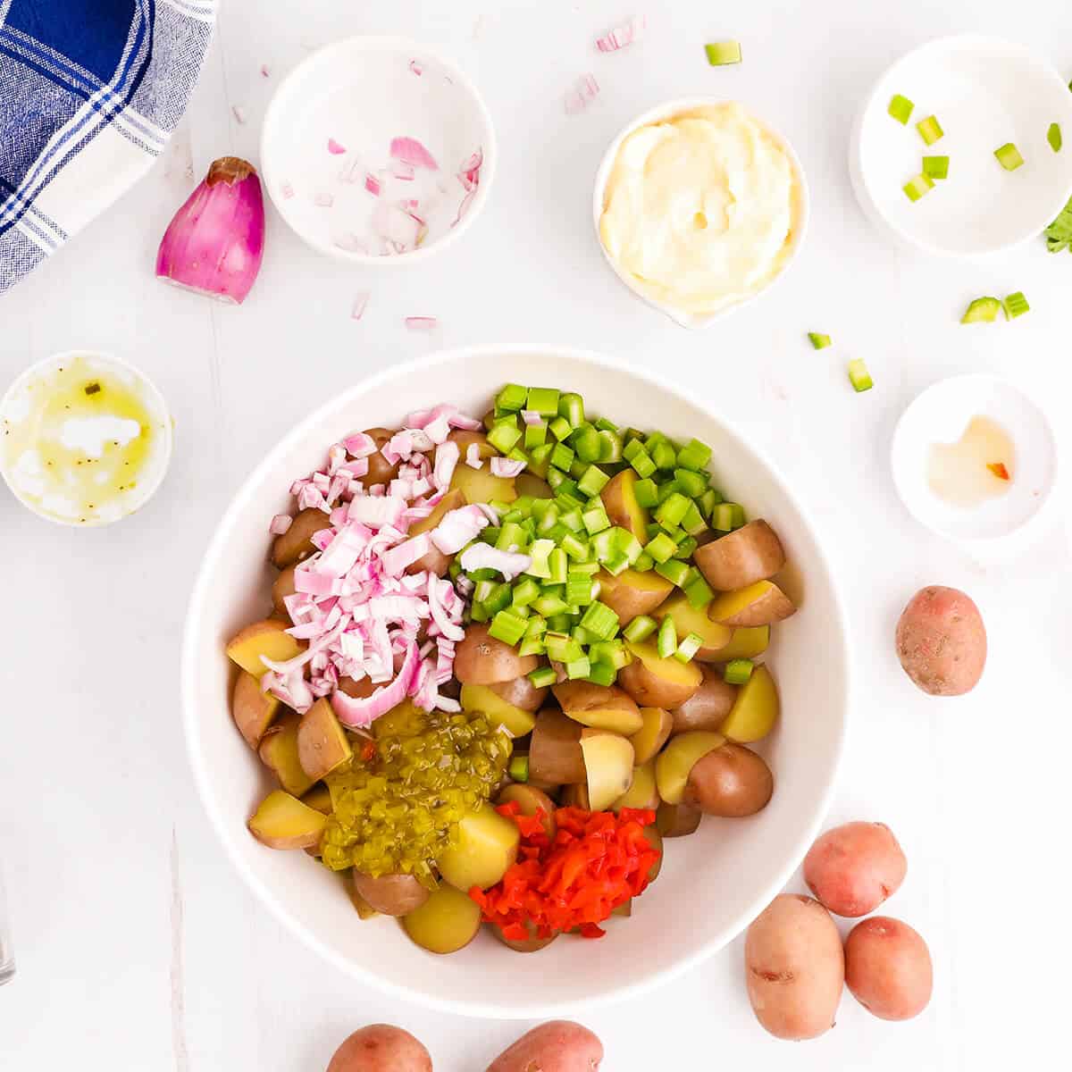 Potatoes, onion, celery, pickles, and pimiento in a mixing bowl.