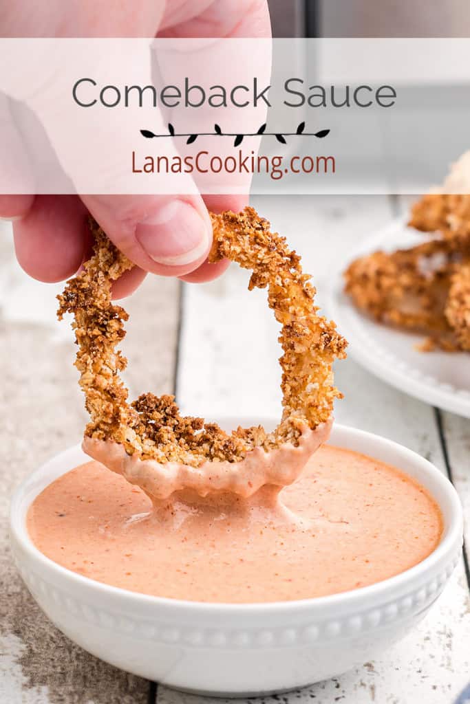 Comeback sauce in a white bowl with an onion ring being dipped.