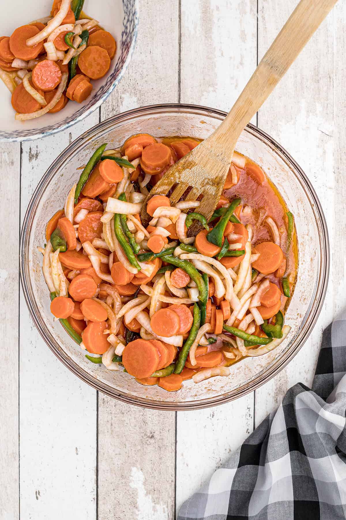 Using a slotted spoon to remove vegetables from the marinade.