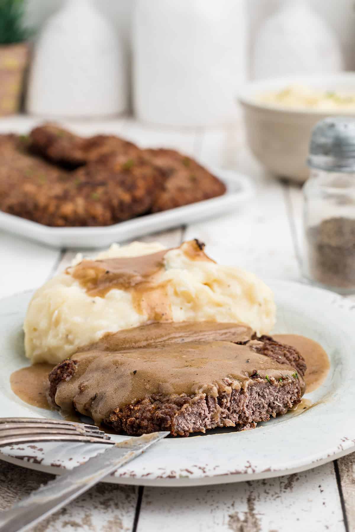 Country fried steak on a plate with gray and mashed potatoes.