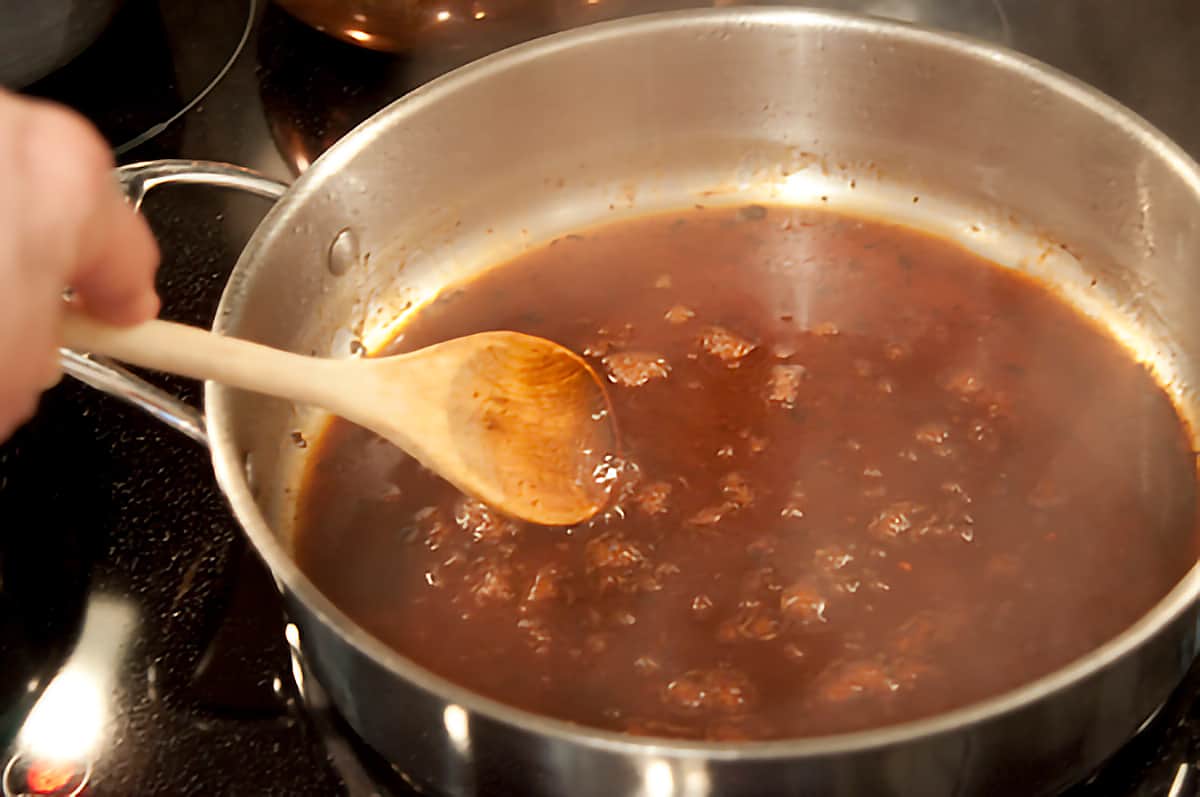 A wooden spoon stirring gravy in skillet