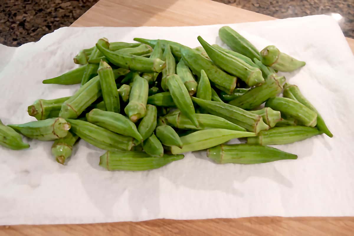 Whole okra pods washed and draining on paper towels.