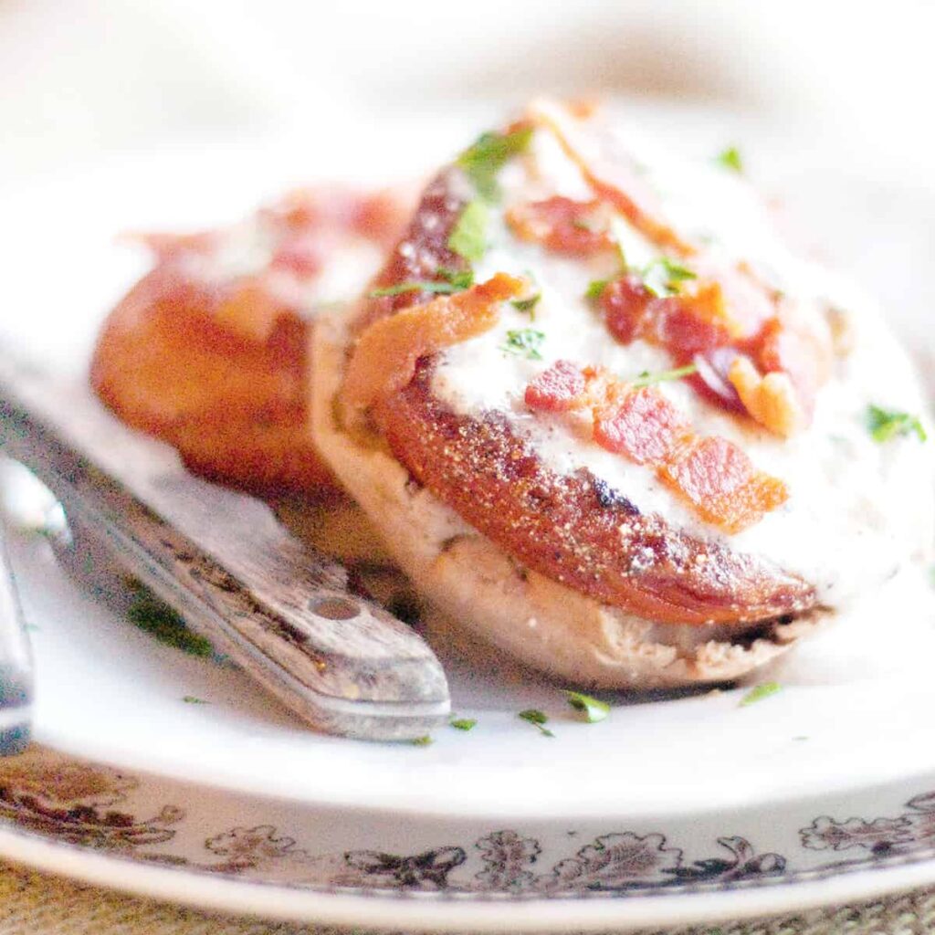 Fried red tomatoes on English muffins with gravy and crispy bacon on top.