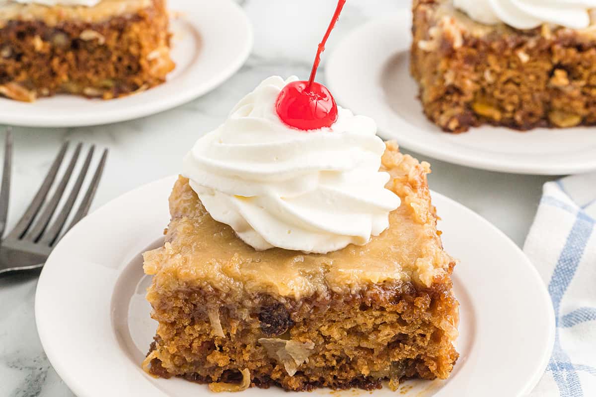 A serving of fruit cocktail cake topped with whipped cream and a cherry.