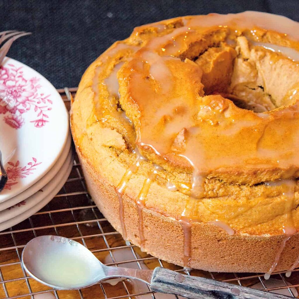 Pumpkin Pound Cake on a wooden board with a spoon and serving plates.