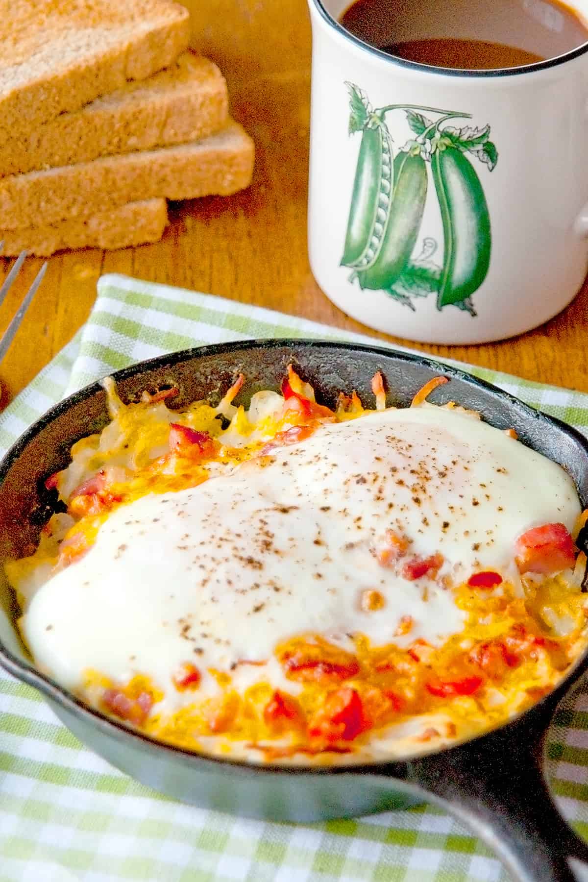 Hash Brown Breakfast Skillet on a kitchen towel with a cup of coffee in the background.