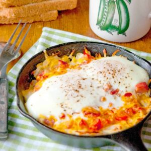 Hash Brown Omelet Skillets on a kitchen towel with a cup of coffee in the background.