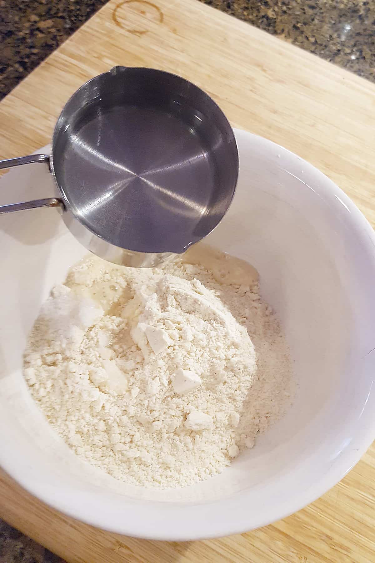 Pouring hot water into the cornmeal in a mixing bowl.