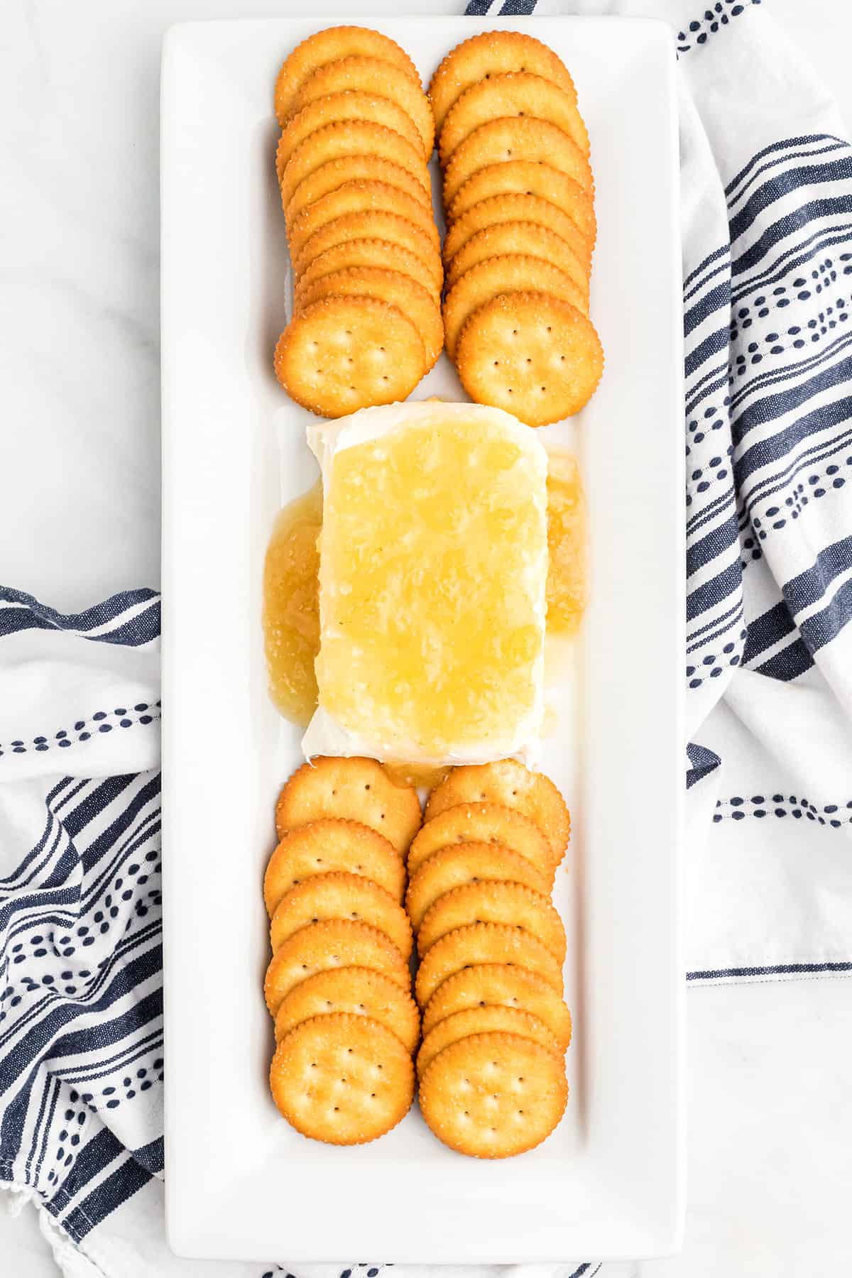 Jezebel sauce poured over a block of cream cheese on a tray with crackers.