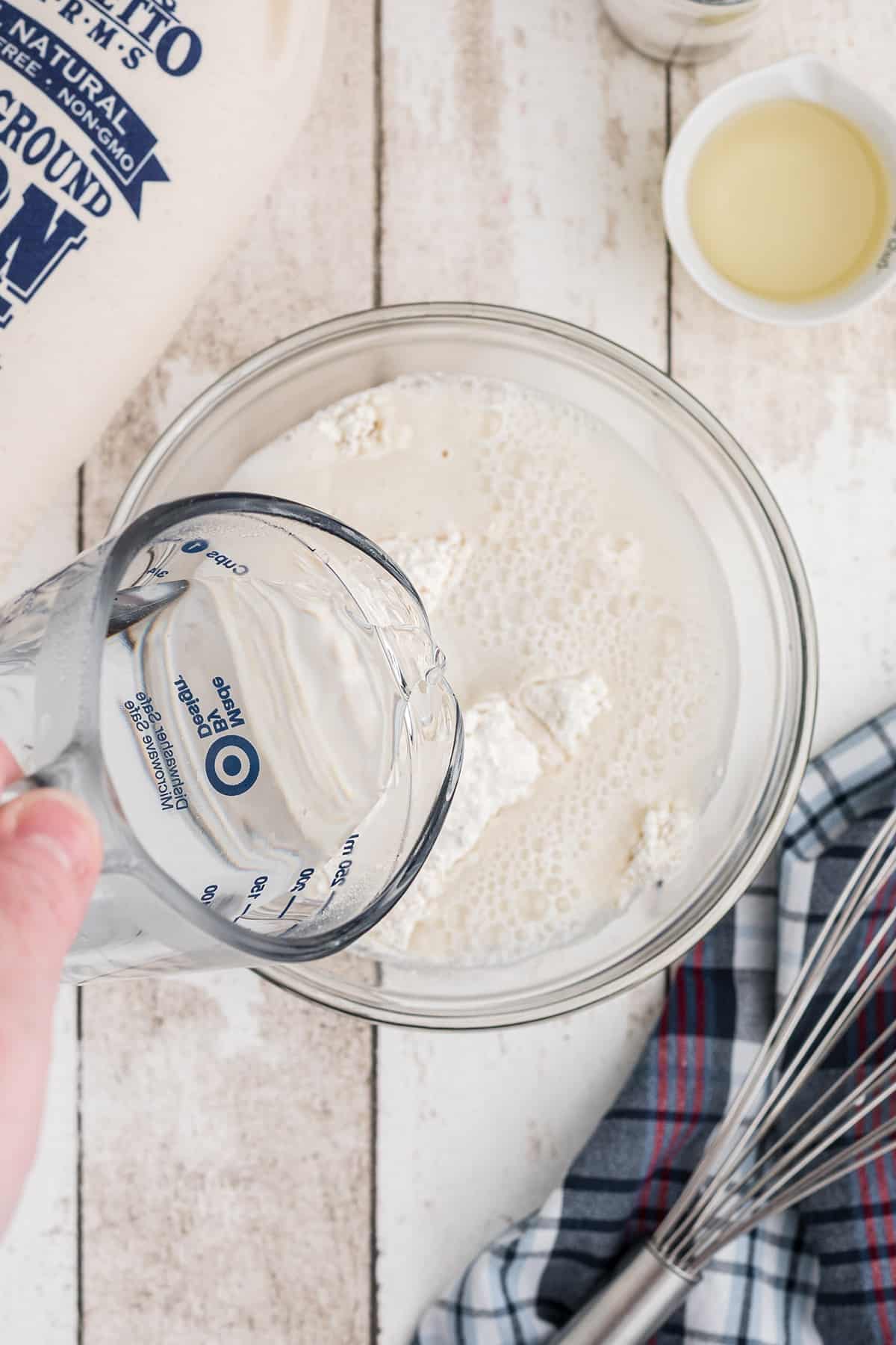 Adding hot water to dry ingredients in a mixing bowl.