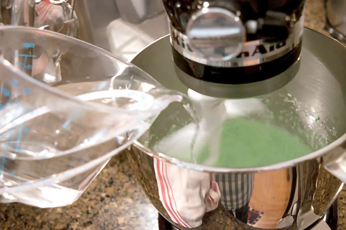 Boiling water being poured into the cream cheese and jello mixture in mixing bowl.