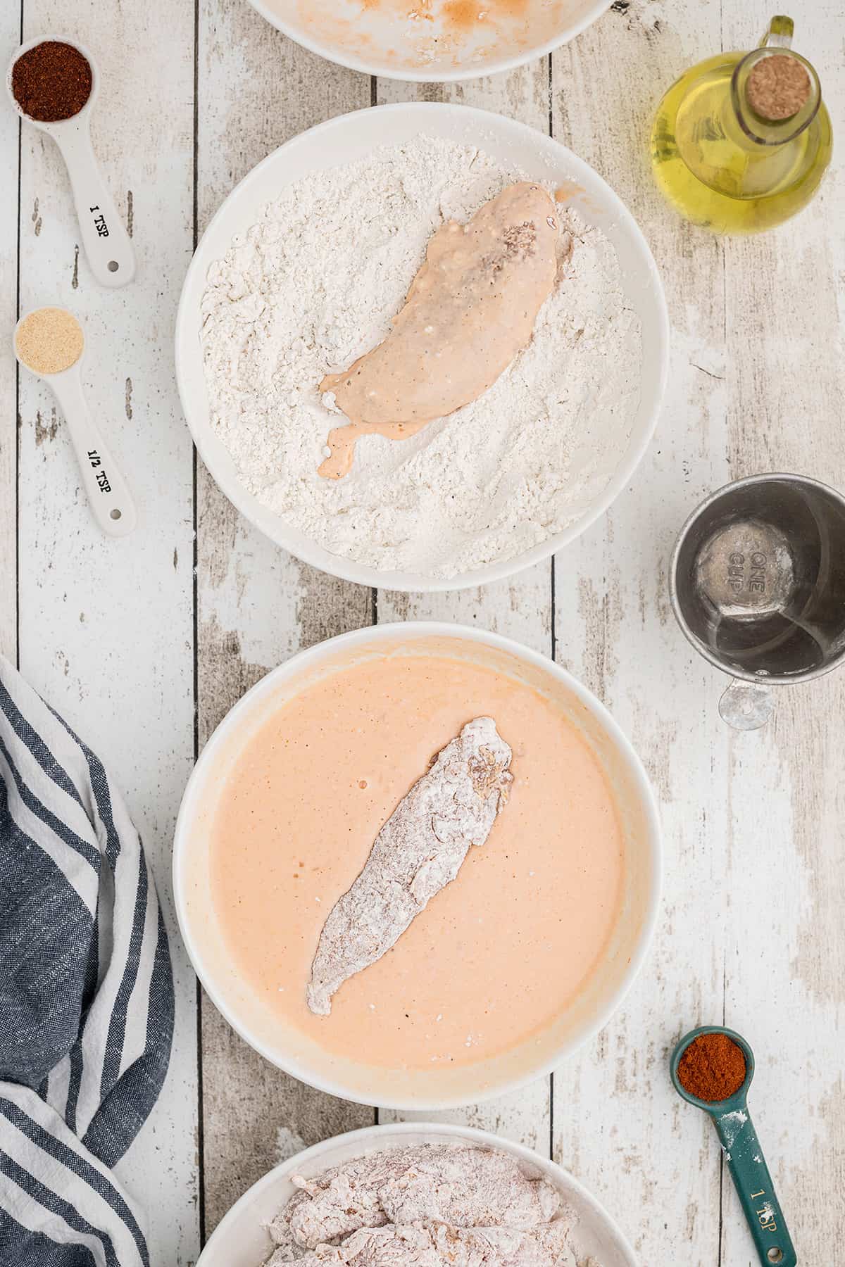 Dipping chicken to coat in buttermilk and flour.