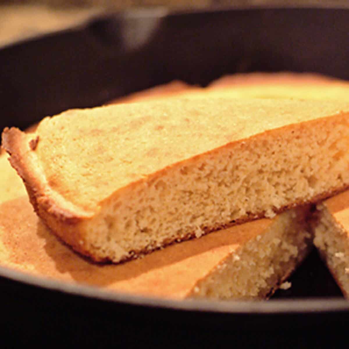 A slice of cornbread on top of a skillet.