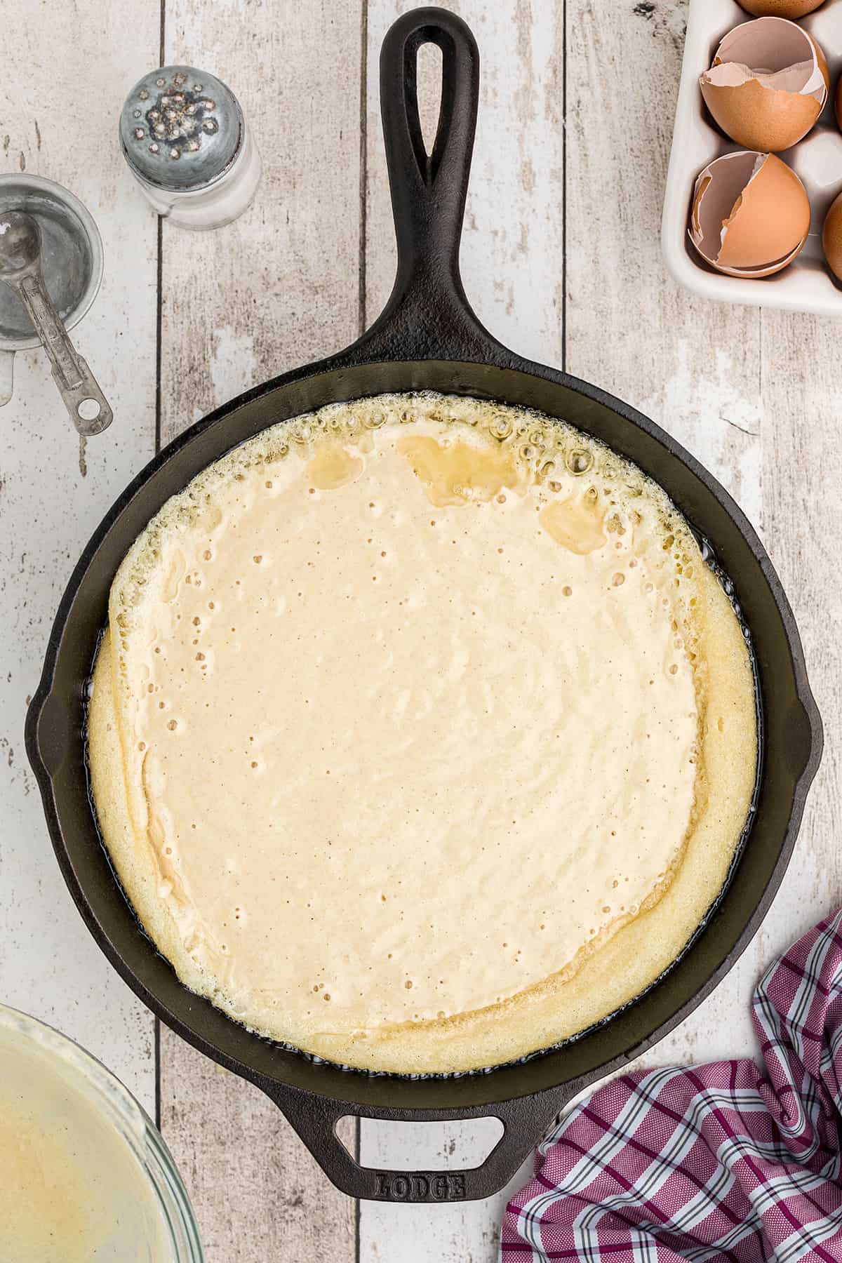 Cornbread batter added to hot oil in skillet.