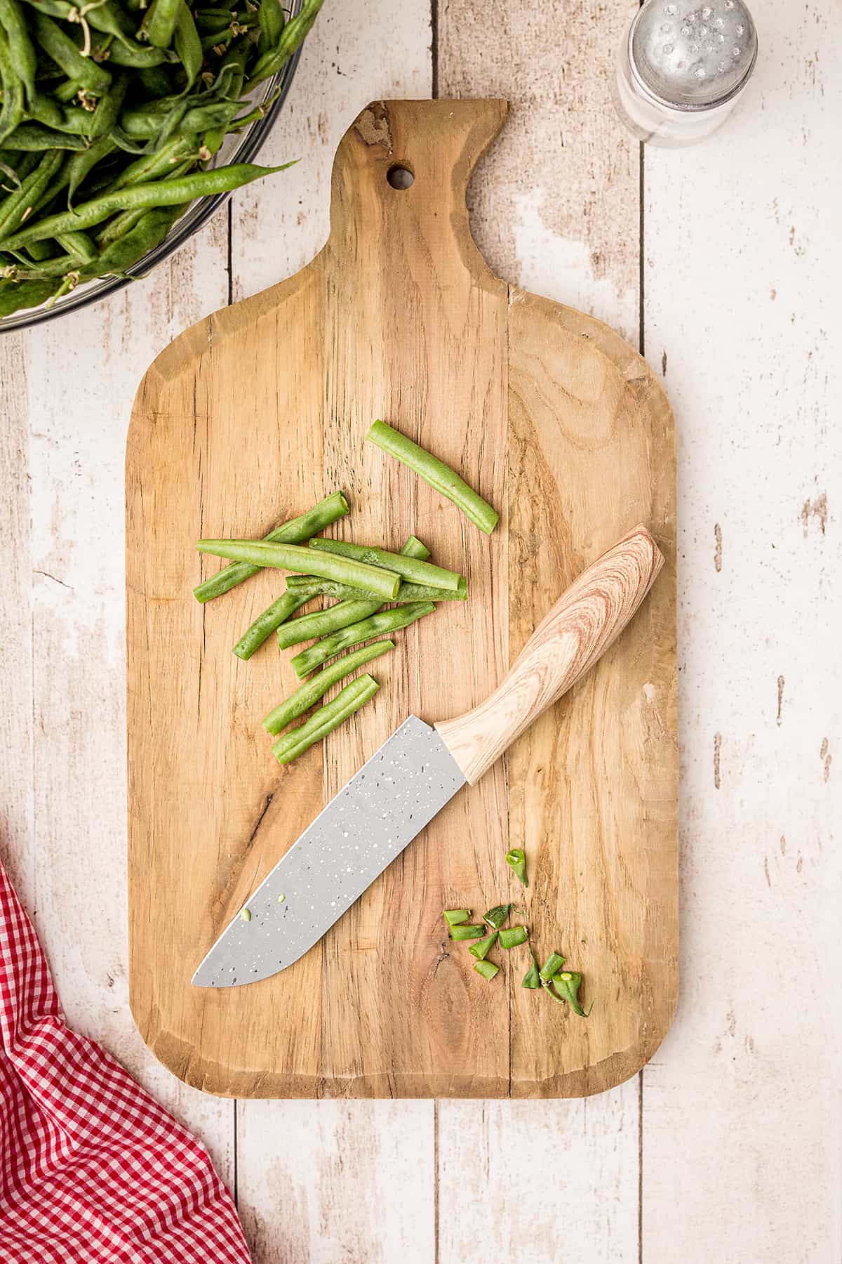 Fresh green beans on a cutting board with a knife.