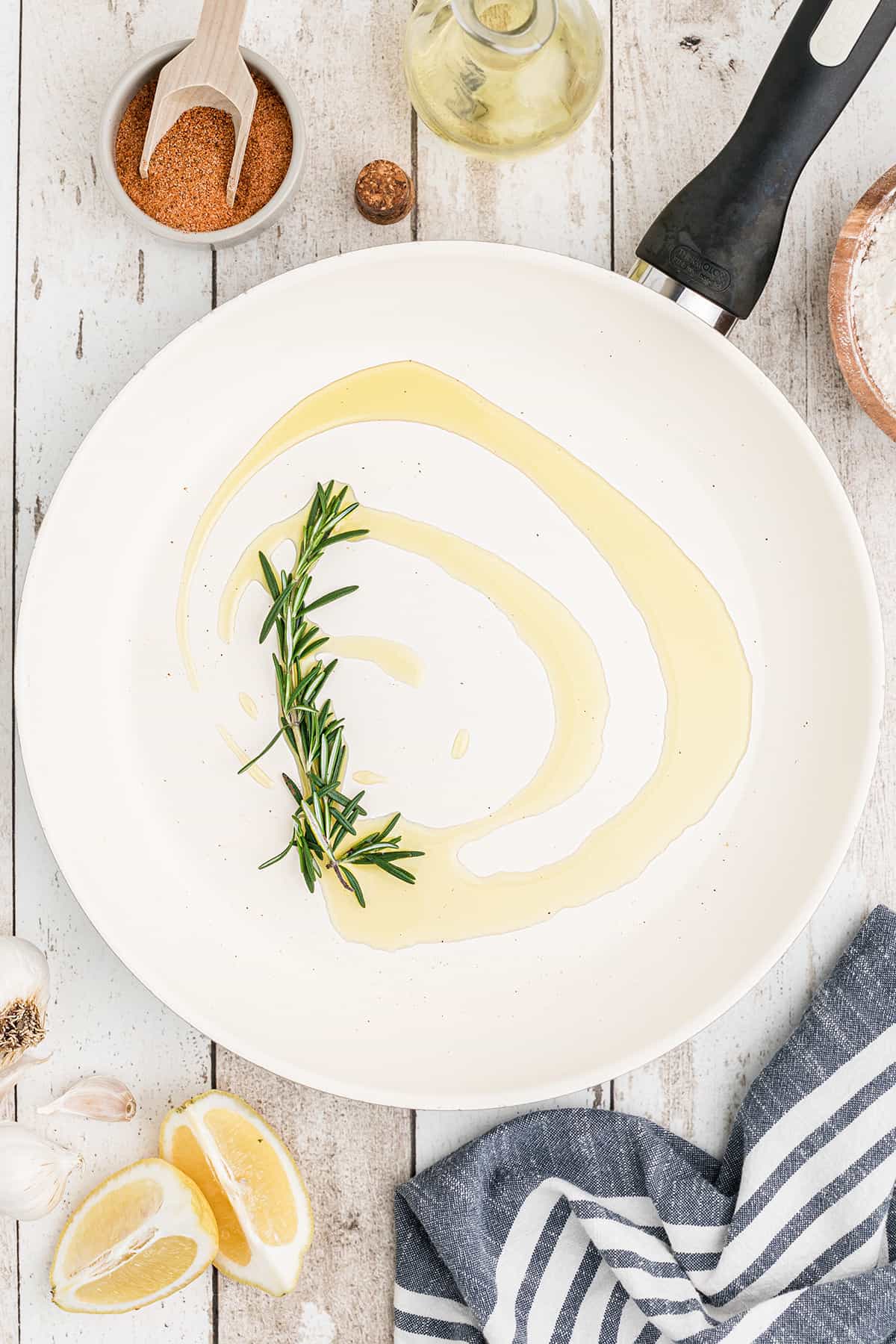 Oil and fresh rosemary heating in a skillet.