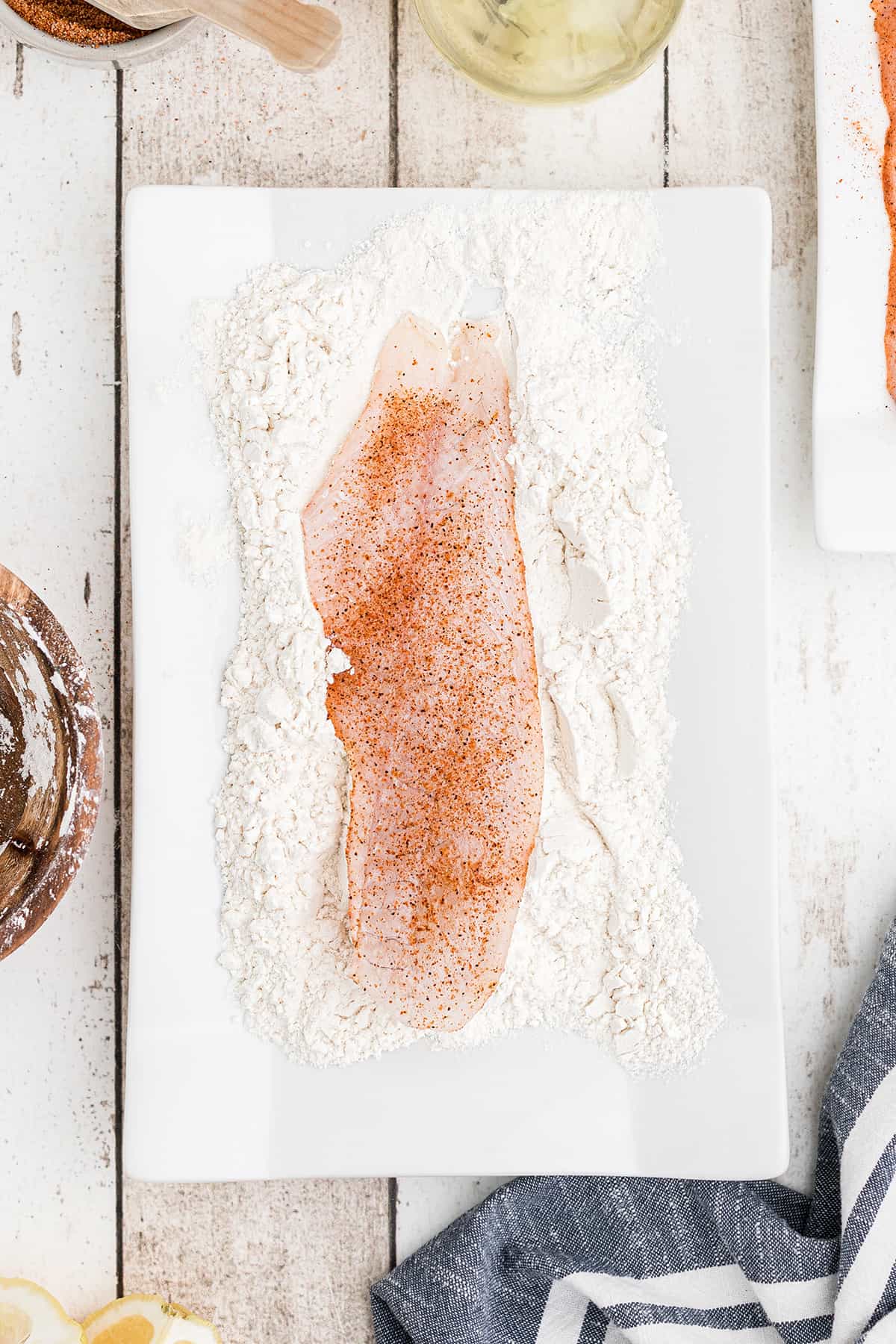 Dredging fish fillets in flour.