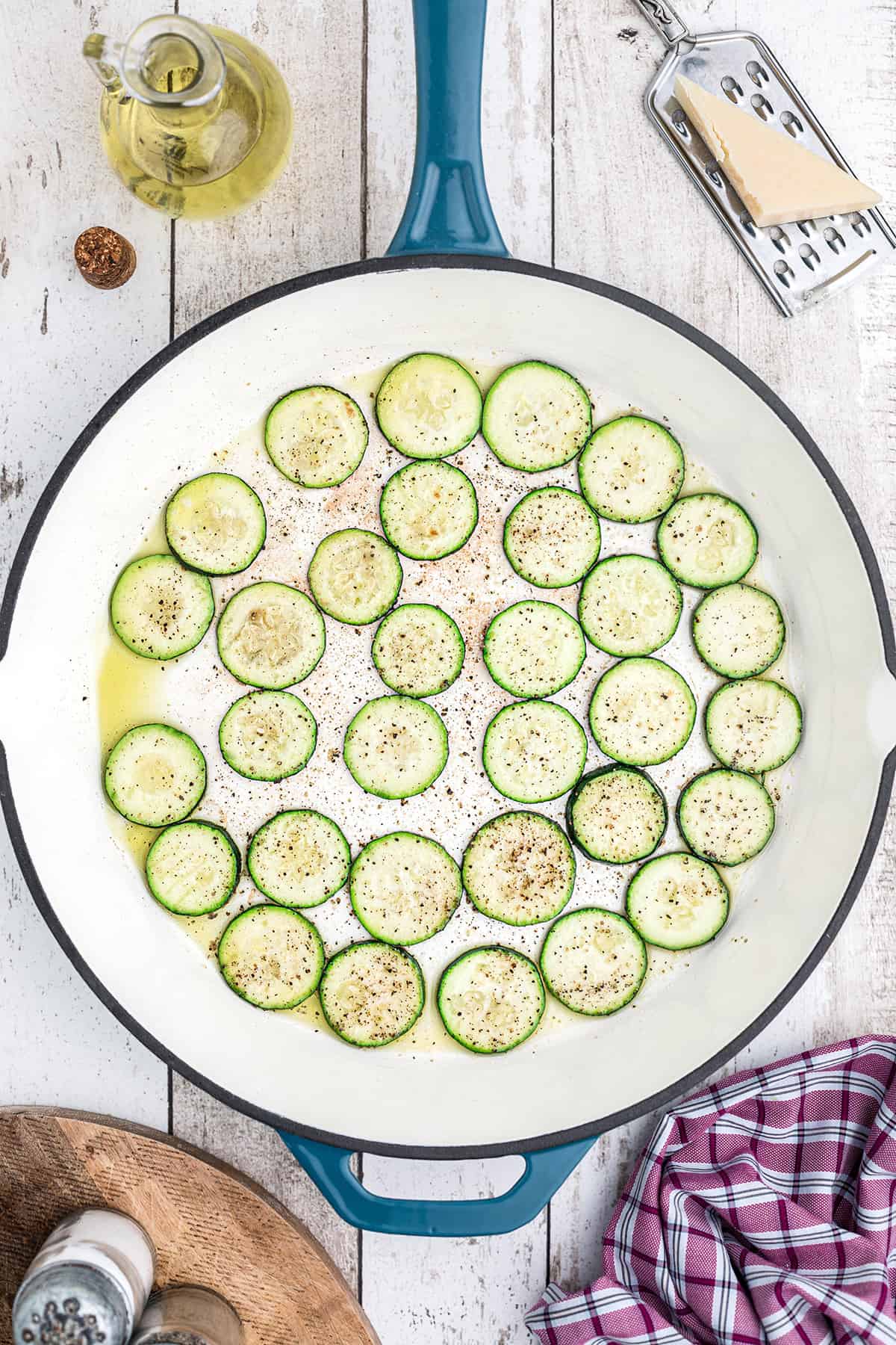 Zucchini slices cooking in a skillet.