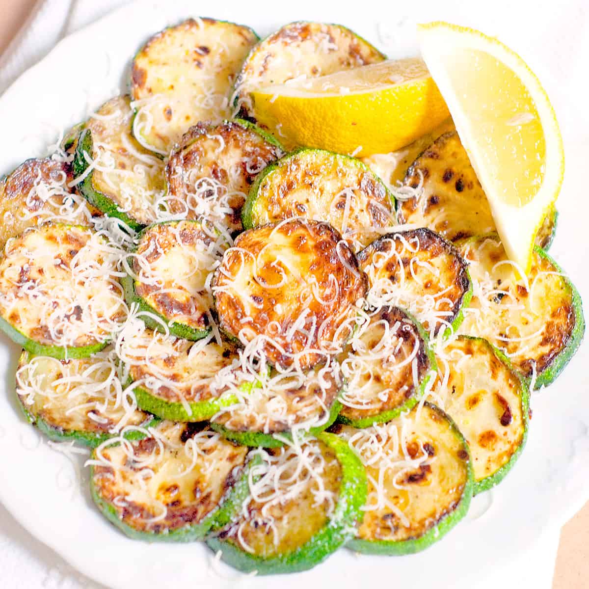 Pan Fried Zucchini with Lemon and Parmesan arranged on a serving plate.