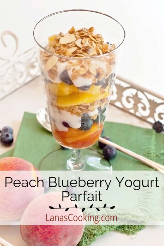 Parfait in a tall glass with a spoon on a tray.