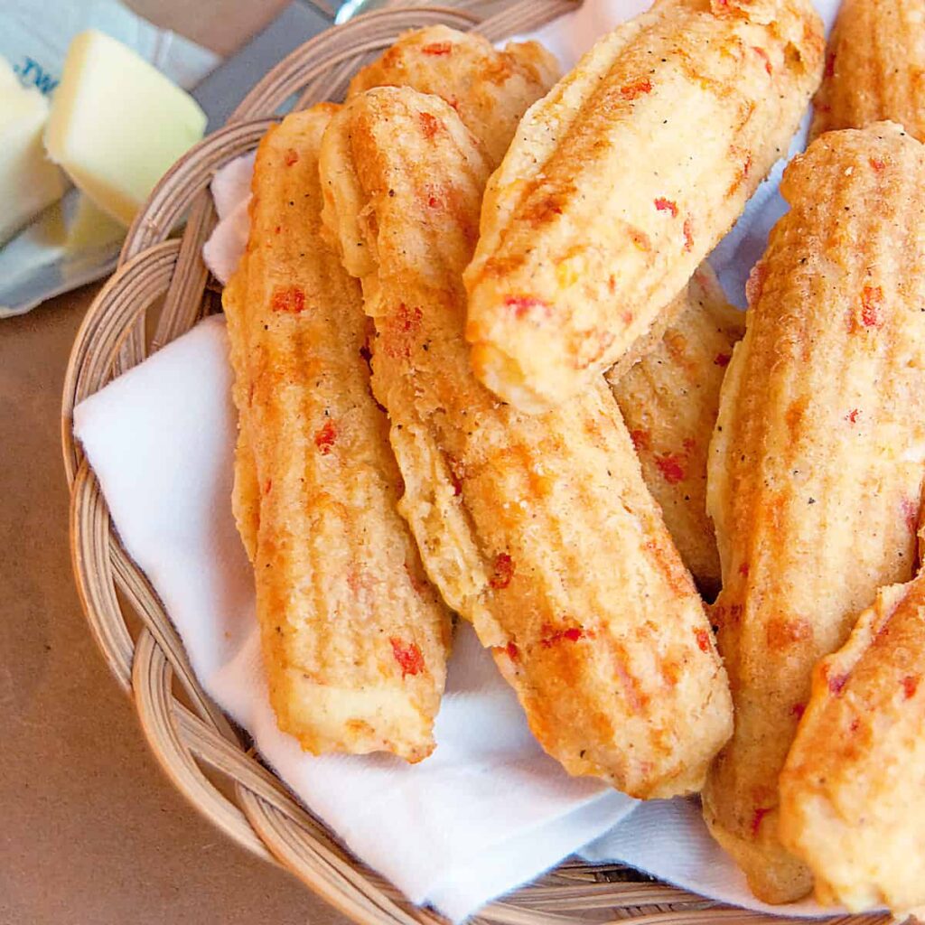 Pimiento Cheese Corn Sticks in a basket with a knife and butter to the side.