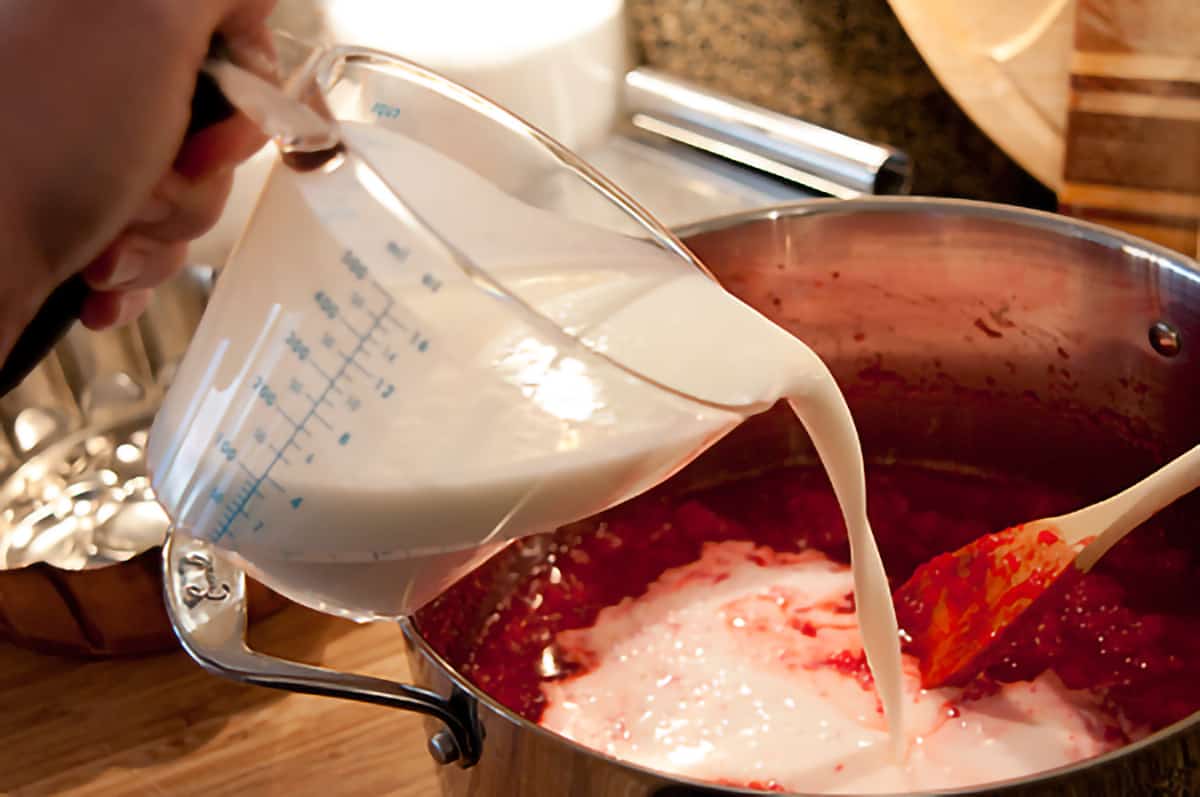 Buttermilk being poured into cooled jello and pineapple mixture.