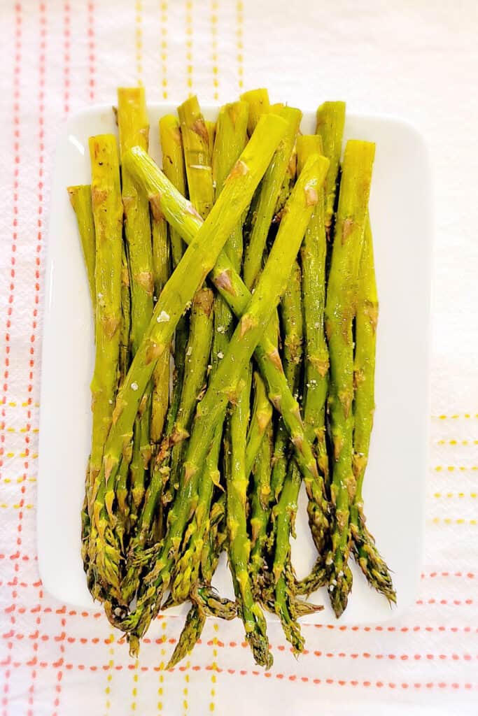 Oven roasted asparagus on a white serving dish.