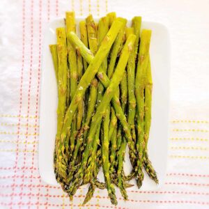 Oven roasted asparagus on a white serving dish.