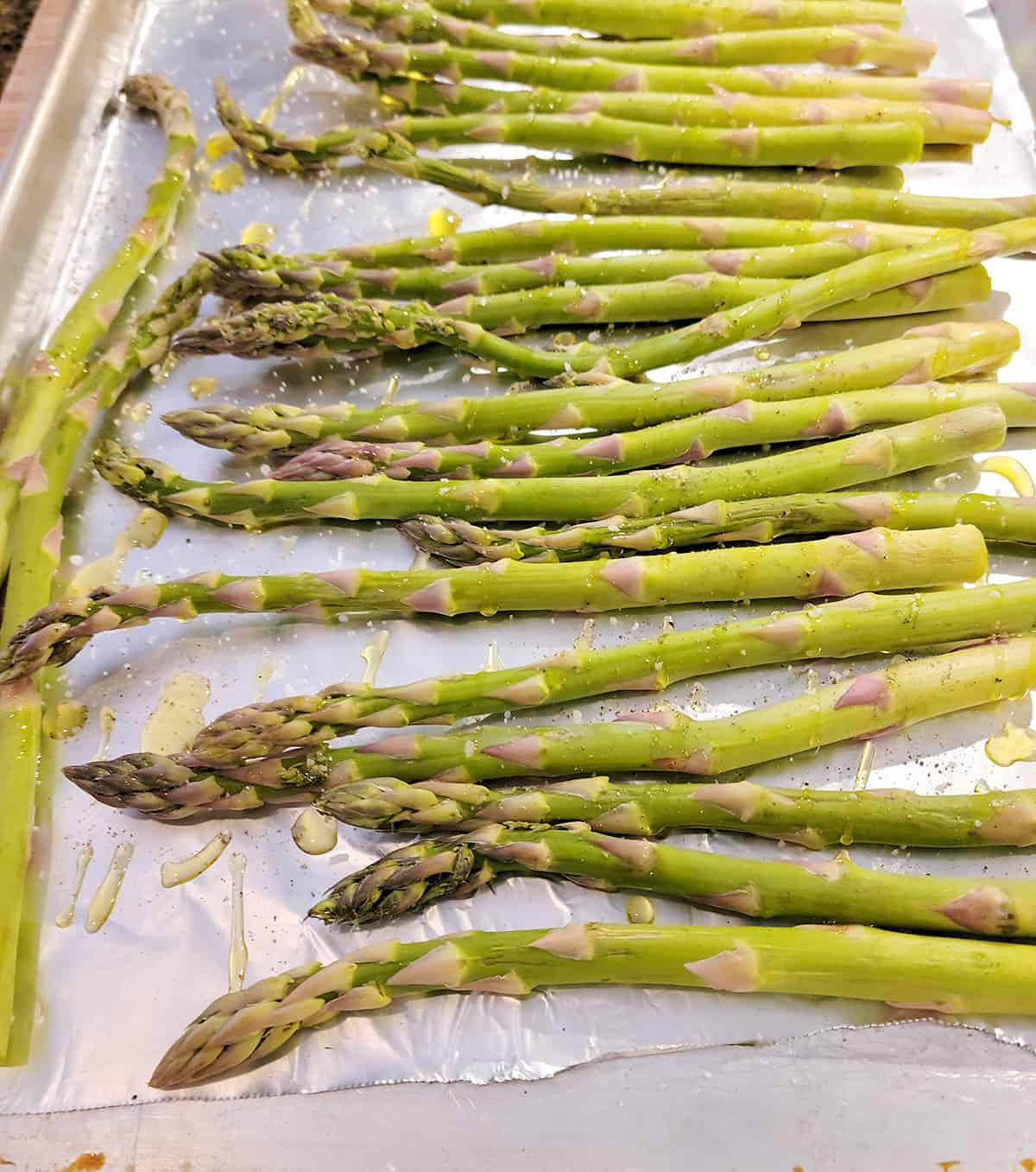 Asparagus on lined baking sheet drizzled with oil.