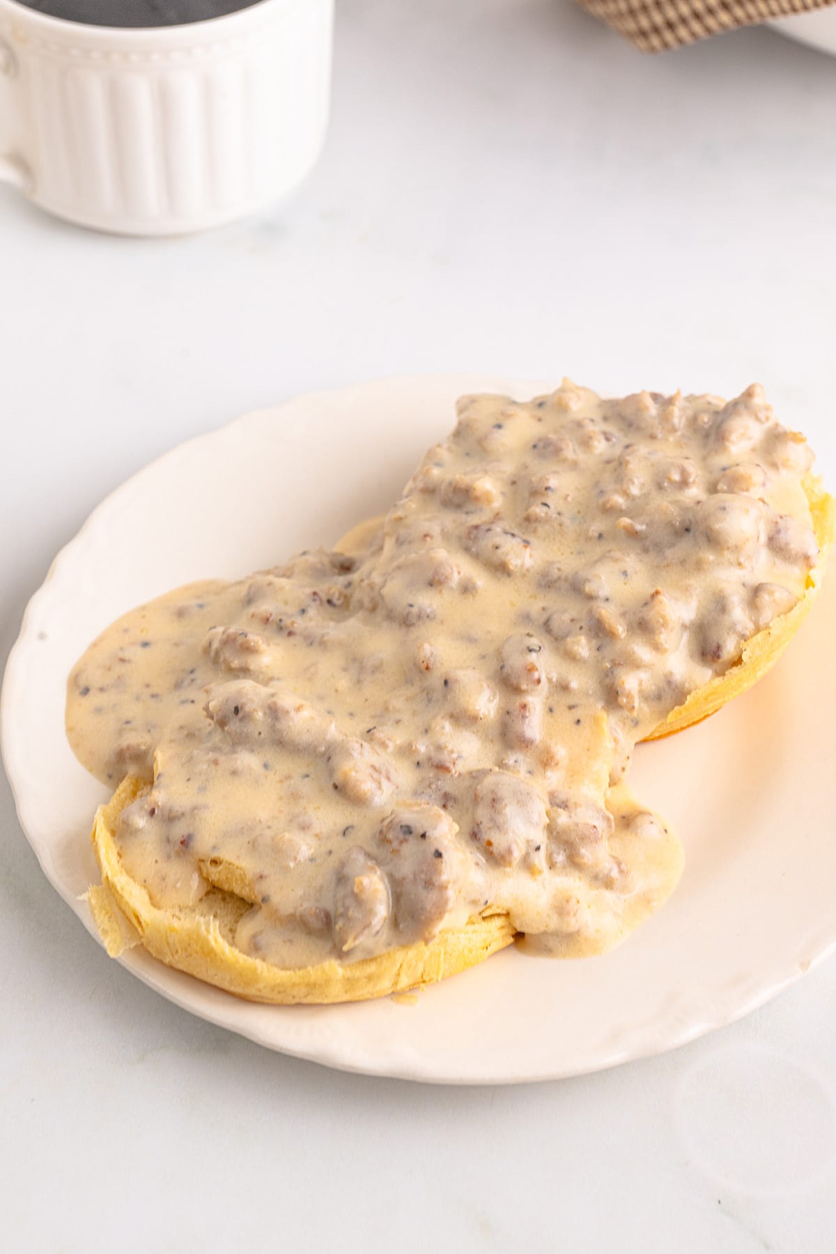 Gravy poured over split biscuits on a plate.