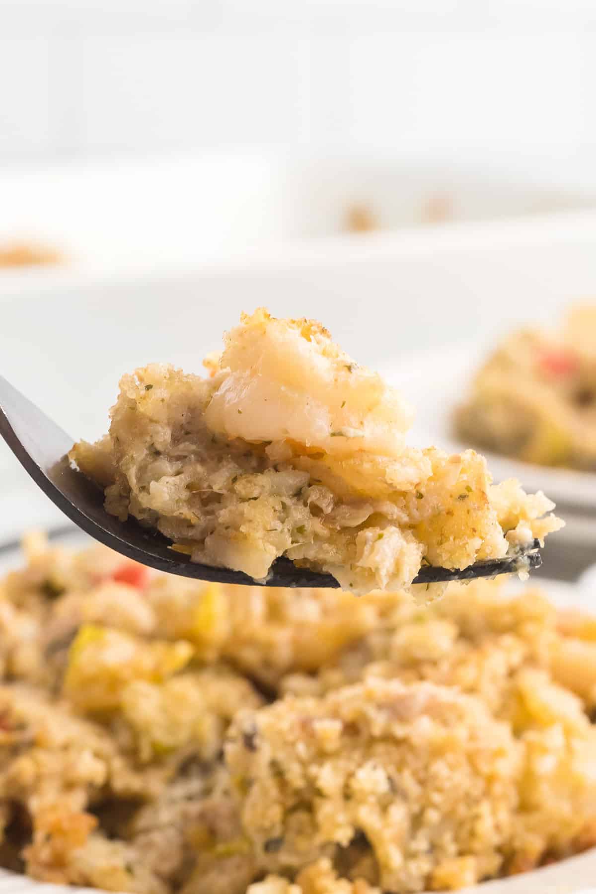 A fork holding a bite of seafood casserole.