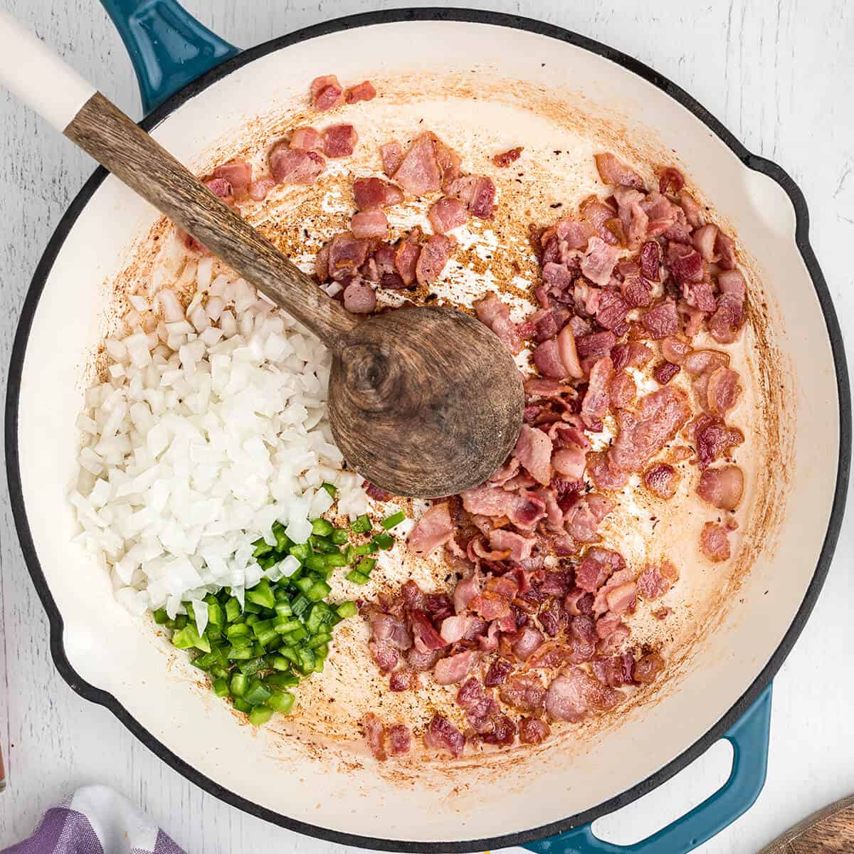 Bell pepper and onion added to cooked bacon in skillet.