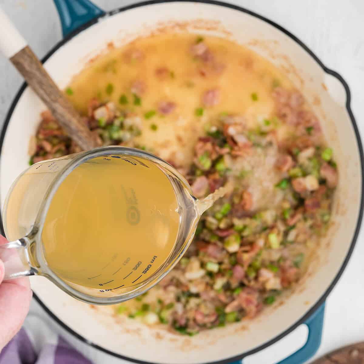 Adding chicken broth into the skillet.