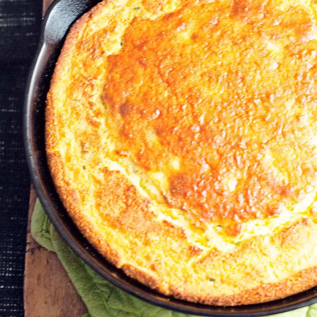 Sour Cream and Onion Cornbread in a cast iron skillet on a hot pad.