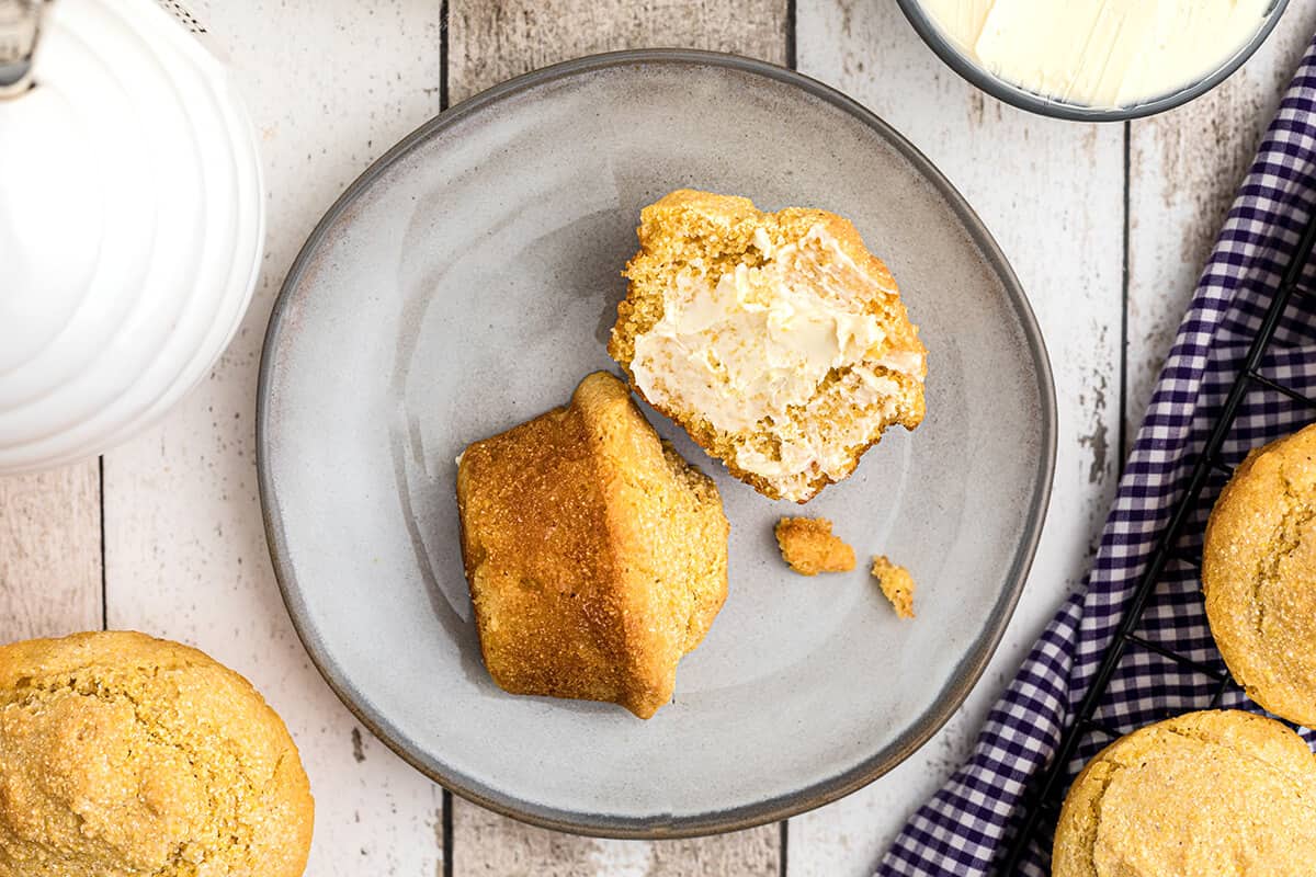 A split muffin on a plate with butter and honey.