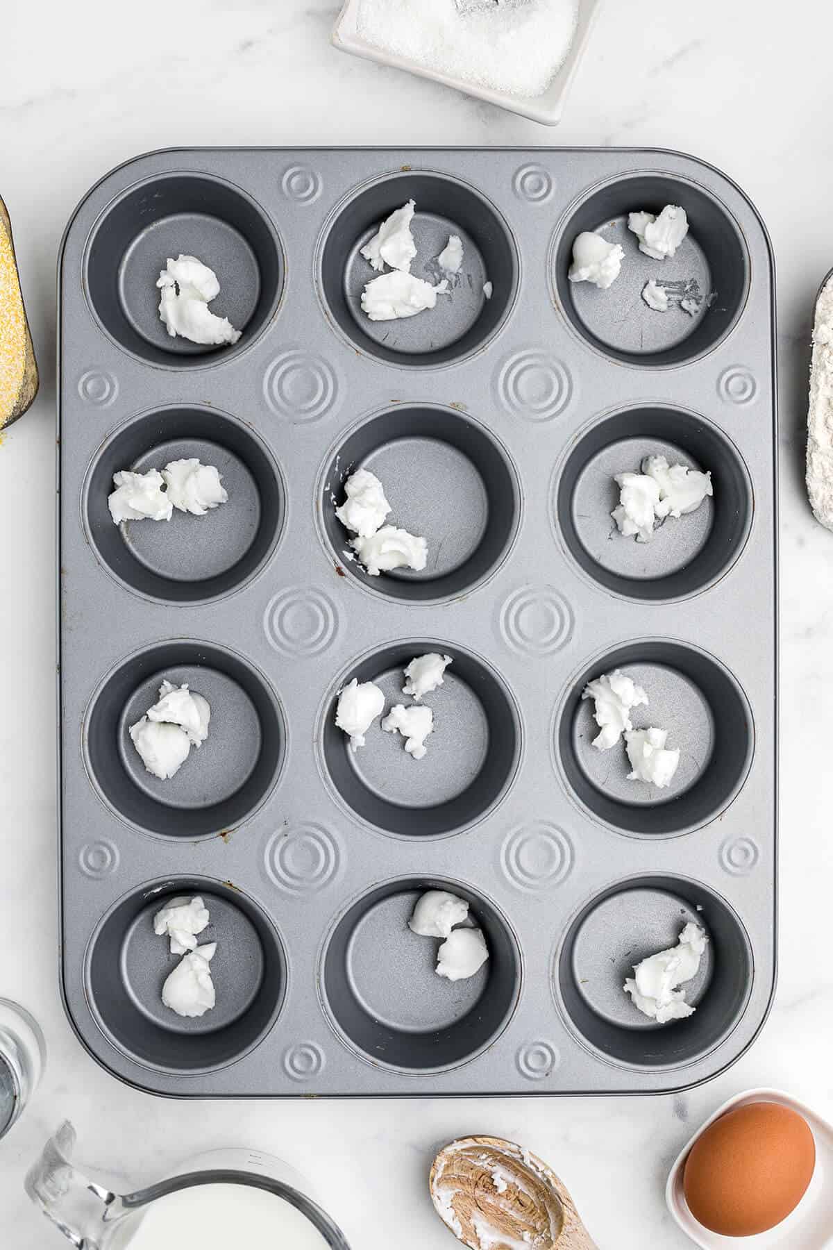 Muffin tin with shortening in each cup.