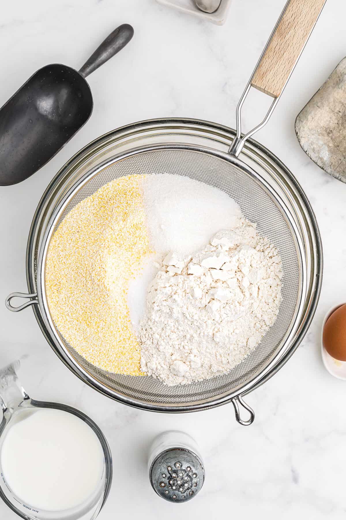 Dry ingredients being sifted into a mixing bowl.