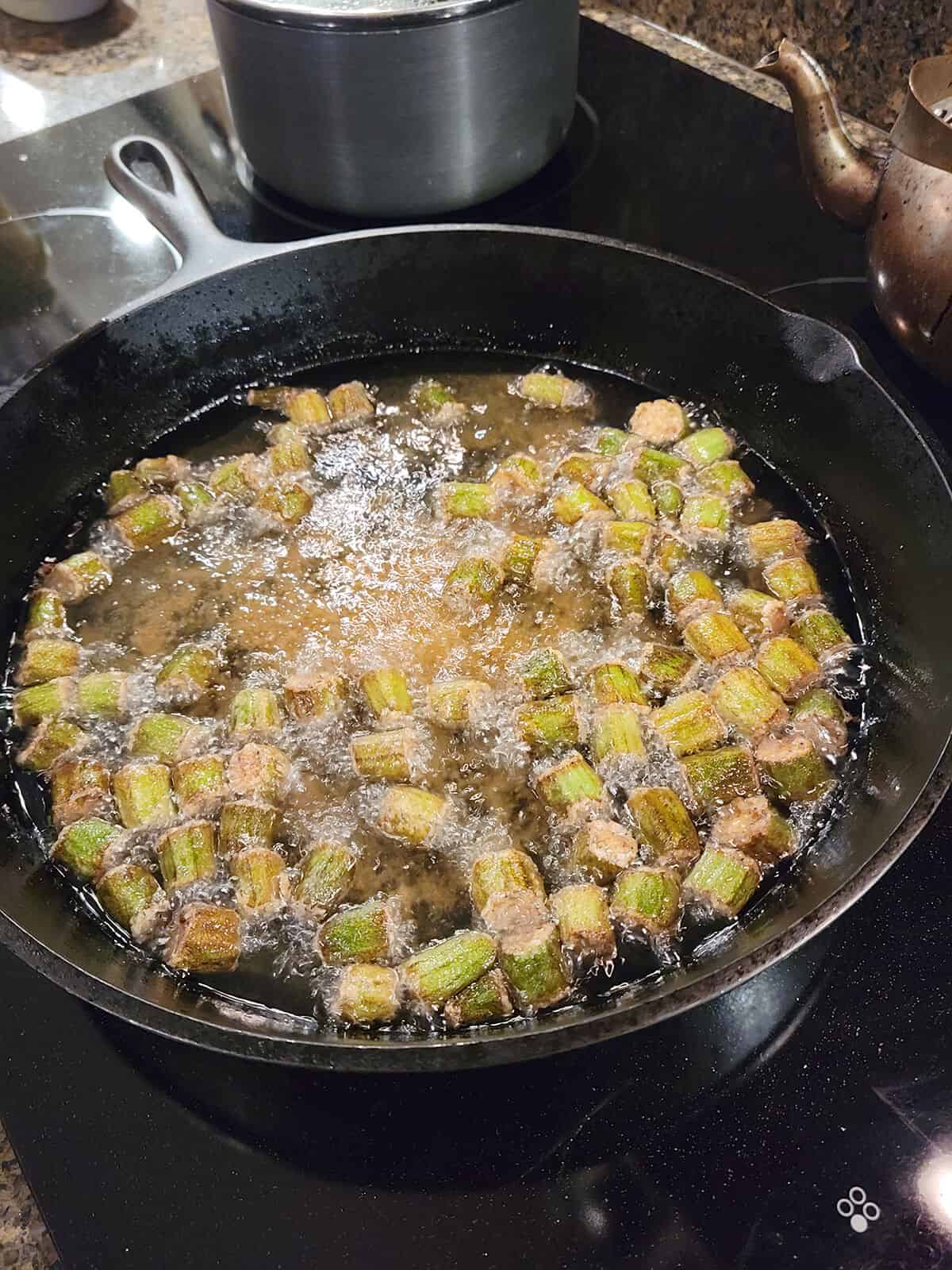 Golden brown okra ready to be removed from the oil and drained.